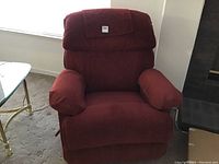 Front view of red-brown Lazy Boy recliner chair in upright position near window and glass side table