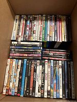 Top-down image of DVDs and Blu Rays stacked neatly in a box, showing various movie titles and cases.