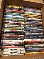 Photo showing a full box of DVDs stacked with titles visible, including family movies, classics, and action films