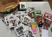 Photo showing wicker basket and variety of novelty napkin packages with vintage photos and amusing captions arranged on table.