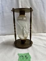 Hourglass timer standing upright showing full structure with three twisted brass pillars and clear glass sand chamber.