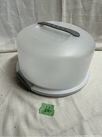 Plastic cake caddy with dome lid secured by clips and handle shown assembled