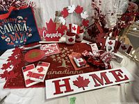 Wide view of the Canada Day decorations including tote bag, signs, candle holders, napkins, coasters, and other items with Canadian maple leaf motif