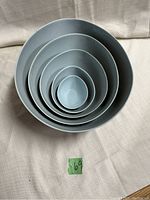 Top down view of five egg shaped nesting bowls nested inside each other showing size gradation and color