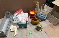 Photo showing various kitchen items including vintage goose egg basket, frog holder, melamine bowls, blue teapot, pumpkin creamer, wooden cat and duck figurines, and kitchen stationary items in a blue tray.