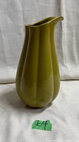 Green ceramic jug or pitcher with fluted body and wide pouring spout, no handle visible.