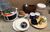 Overview of kitchen items including Lazy Susan turntable, plates, mugs, wooden claws, containers, basket, and other utensils on a cardboard base.