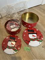 Three nesting cookie tins with snowman holiday design, plastic wrapping removed from the top tin, tins displayed nested and separated to show different sizes.