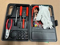 Top view of open toolbox showing organized hand tools, electrical accessories, and white work glove.