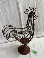 Front view of the rustic metal rooster showing the twisted metal rod design and round base