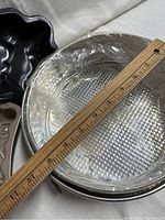 Photo showing round metal springform pan with attached latch, plastic wrapped cake base and wooden ruler for size reference