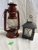 Overview photo showing both the red vintage oil lamp and black candle lantern side by side on a white background.