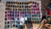 Photo showing 113 Yu-Gi-Oh cards arranged on white cloth surface in rows, revealing variety of monster, spell, and trap cards with colorful illustrations.