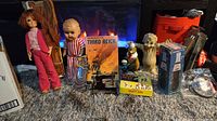 Image showing two dolls, vintage Third Reich board game, ceramic animal figurines, a metal sewing machine box, and other assorted vintage collectible items arranged on floor.