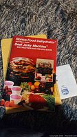 Instruction and recipe book for Ronco Food Dehydrator and Beef Jerky Machine, with colorful front cover showing dehydrator and food items.