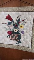 Front view of the 28 inch square patchwork quilted wall hanging with floral basket centered.