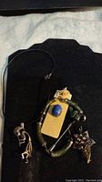 Photo of Kokopelli necklace choker, jade bracelet, lapis lazuli pin, and silver brooch on black background.