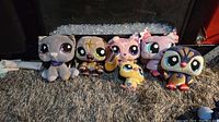 Full view of all six Littlest Pet Shop plush toys placed on a carpeted surface with reflective background.