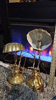 Side-by-side view of two matching adjustable solid brass desk lamps approximately 18 inches tall, showing shell-shaped shades and solid bases.