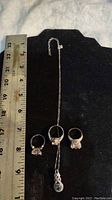 Full view of three sterling silver rings and adjustable necklace with ruler for size reference.