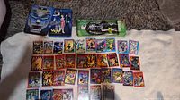 Full lot featuring multiple trading cards spread out on cloth with two boxed figurines ready for display.