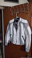 Full view of the Swift motorcycle riding jacket hanging showing white and gray color with mesh and padded sections.