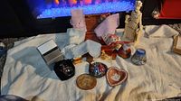 Full lot of various vintage trinkets laid out on a white cloth including Wedgewood dish, pewter figurines, perfume bottles, and handkerchiefs