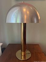 Front view of the lamp showing dome-shaped silver/chrome shade with reflections and brass stem and base.