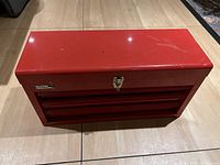 Front view of closed red metal toolbox showing Master Mechanic brand label and latch.
