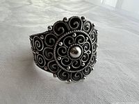 Front angle view of ornate silver cuff showing central filigree medallion and bead accents