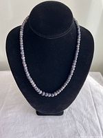 Front view of the raw faceted sapphire graduated necklace displayed on a black bust, showing the faceted blue-gray stones and graduated bead size.