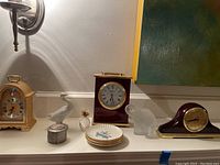 Shelf with five clocks, goose, pineapple, elephant, pewter box, coasters