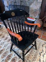 Photos show black wooden captain's chairs with Belmont Hill and Harvard school emblems on backrests, near fireplace and carpeted area.