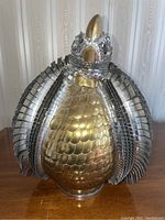 Front view of mixed metal mosaic aardvark sculpture on wooden surface