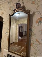 Full view of the ornate wall mirror showing its rectangular shape and decorative wallpaper background.