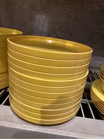 Stack of yellow vintage hard plastic plates on a shelf