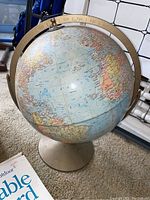 World globe on metal axis ring and off-white base showing Atlantic Ocean