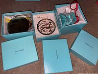 Three open Tiffany blue boxes showing crystal disc, reindeer circle and sleigh ornaments
