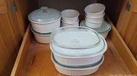 Full shelf view showing all bakeware items, including 1 large oval dish with lid, 2 round dishes with lids, and 7 small ramekins without lids.