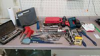 Overview of various tools including a ratchet set, screwdriver bits, bolt cutters, chargers, and batteries on a grey counter.
