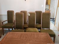 Six dining chairs arranged behind table showing upholstery and frame