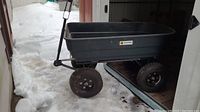 Side view of garden cart showing black plastic tub, steel frame and four pneumatic wheels