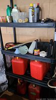 Photo showing red and orange plastic jerry cans on lower shelves, with assorted oil bottles and funnels on upper shelves