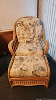 Front view of rattan chair and ottoman with floral cushions