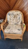 Front view of rattan armchair showing frame and floral-patterned cushions
