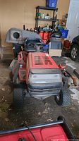 Front view of red riding mower showing hood, grille and front tires