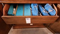 Drawer with four blue fabric rolls containing flatware sets