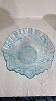 Top view showing the open rose floral embossed pattern and ruffled edge with opalescent light blue color.