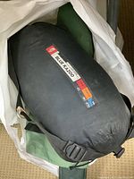 North Face Blue Kazoo sleeping bag in black compression sack with visible label showing 600 fill down and temperature ratings.