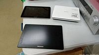 Top view of Toshiba portable DVD player (white), Lenovo tablet (black), and Samsung tablet (black) placed on white surface